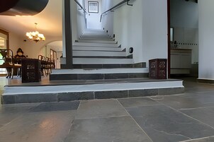 Uma escadaria que leva a um andar superior, com uma área de refeições e cozinha visíveis ao fundo.