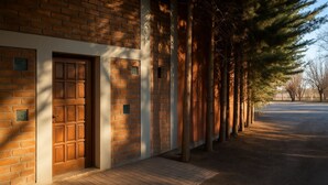 Un edificio con facciata in mattoni, una porta in legno e un'area d'ingresso pavimentata.