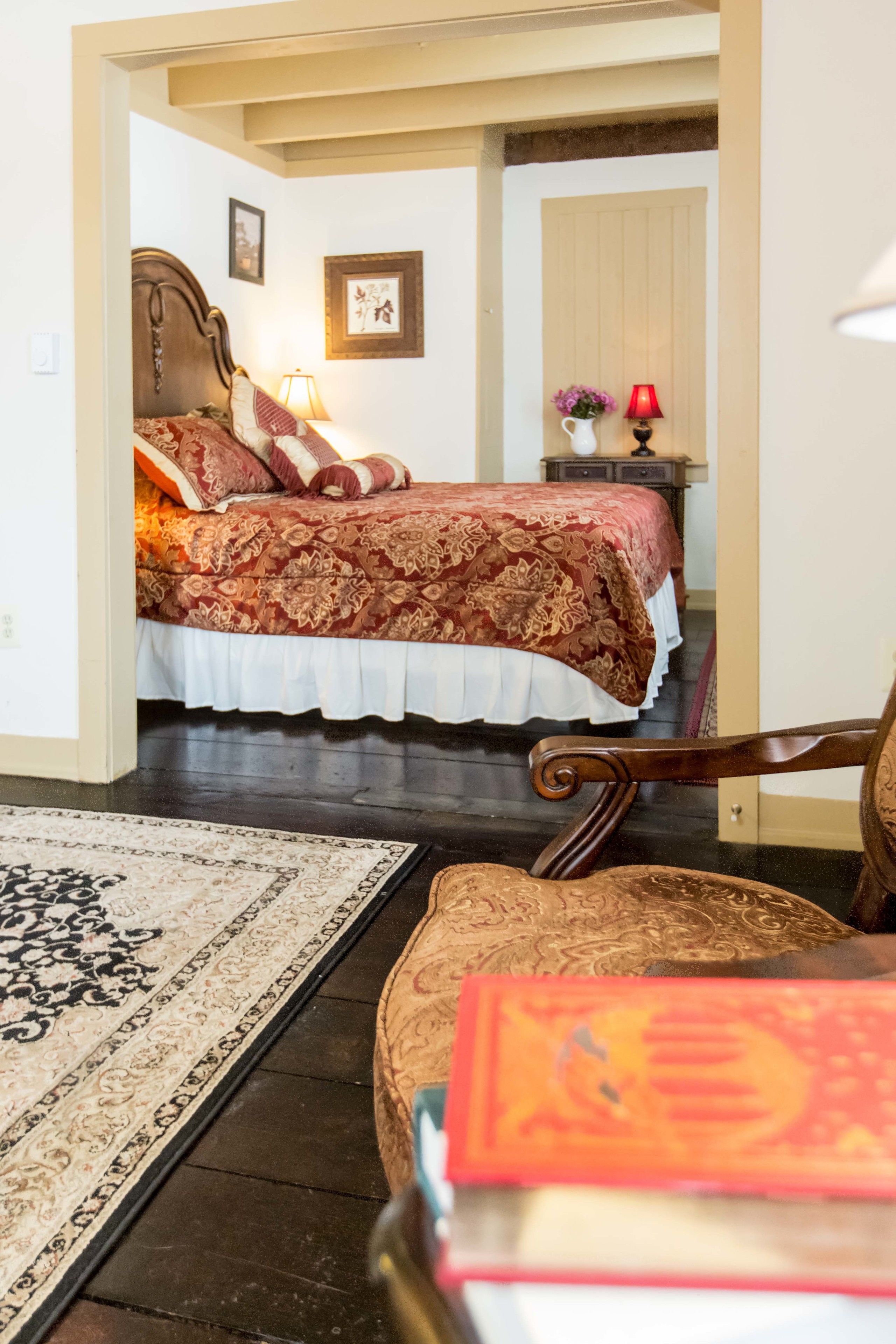 A bedroom with a large bed, a nightstand, a lamp, and a chair.