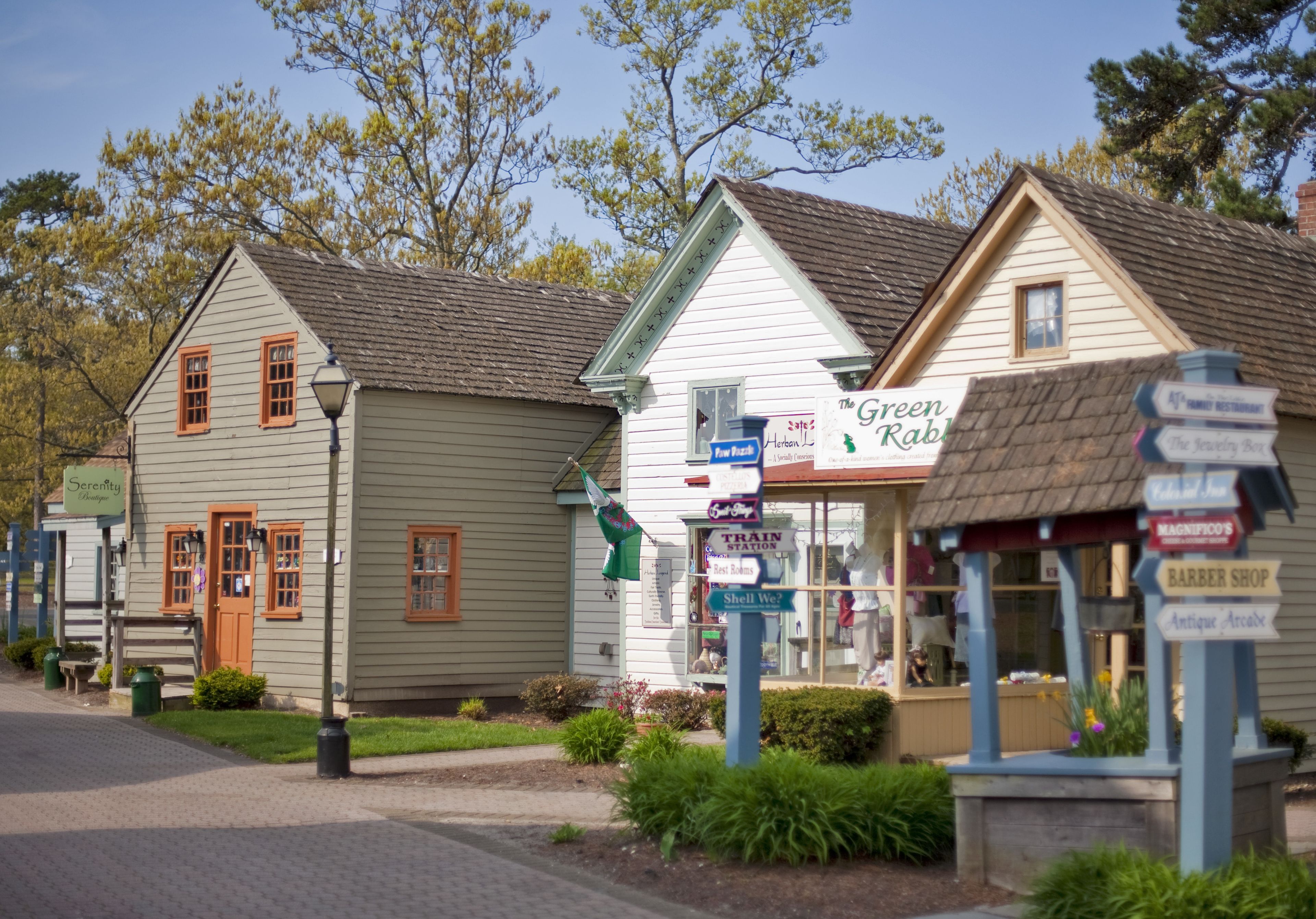 A row of buildings with signs indicating various businesses such as a restaurant, a train station, and a barber shop.