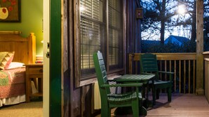 Una stanza con un letto, un comodino, una poltrona verde, un tavolo e una finestra con vista su un patio.