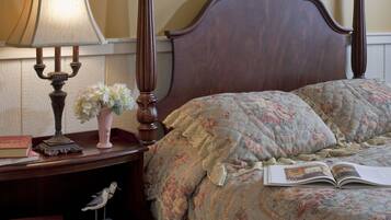 Une chambre à coucher avec une tête de lit en bois, une table de chevet avec une lampe, un vase de fleurs et un livre.