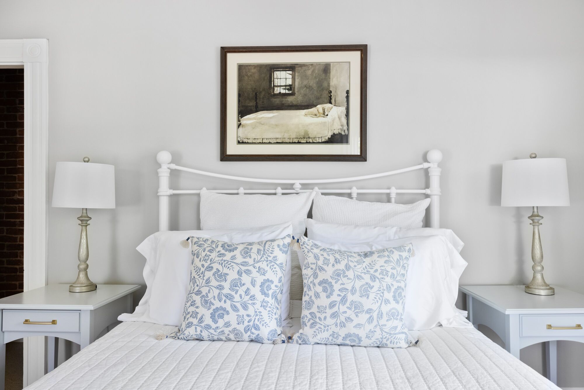 Un dormitorio ordenado con una cama blanca, mesitas de noche a juego y un cuadro en la pared.