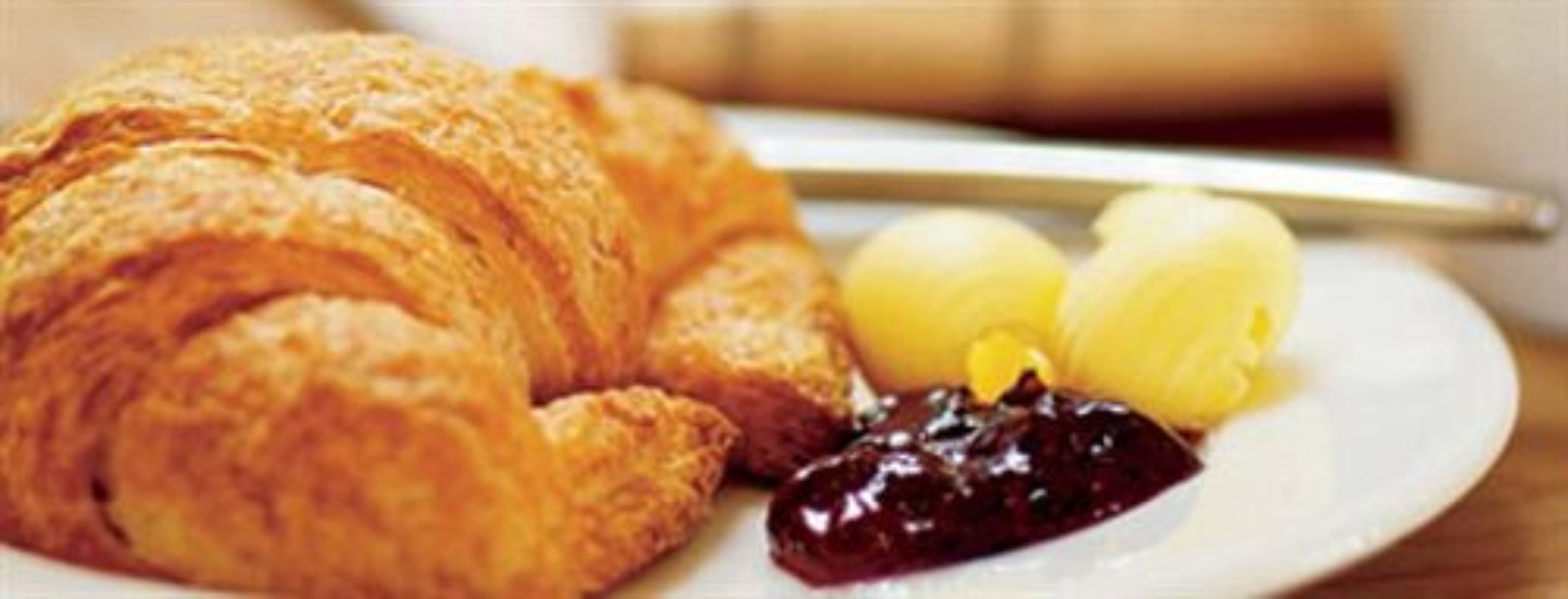 A croissant, two boiled eggs, and a dollop of jam on a plate.