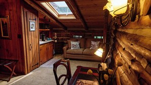 A cozy log cabin interior with a dining area, a sofa with decorative pillows, and a kitchen area with a microwave. - Chalet of Canandaigua (Canandaigua)