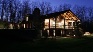 A log cabin with a large deck and multiple windows, surrounded by trees. - Chalet of Canandaigua (Canandaigua)
