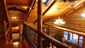 A wooden interior with a staircase, chandeliers, and large windows. - Chalet of Canandaigua (Canandaigua)
