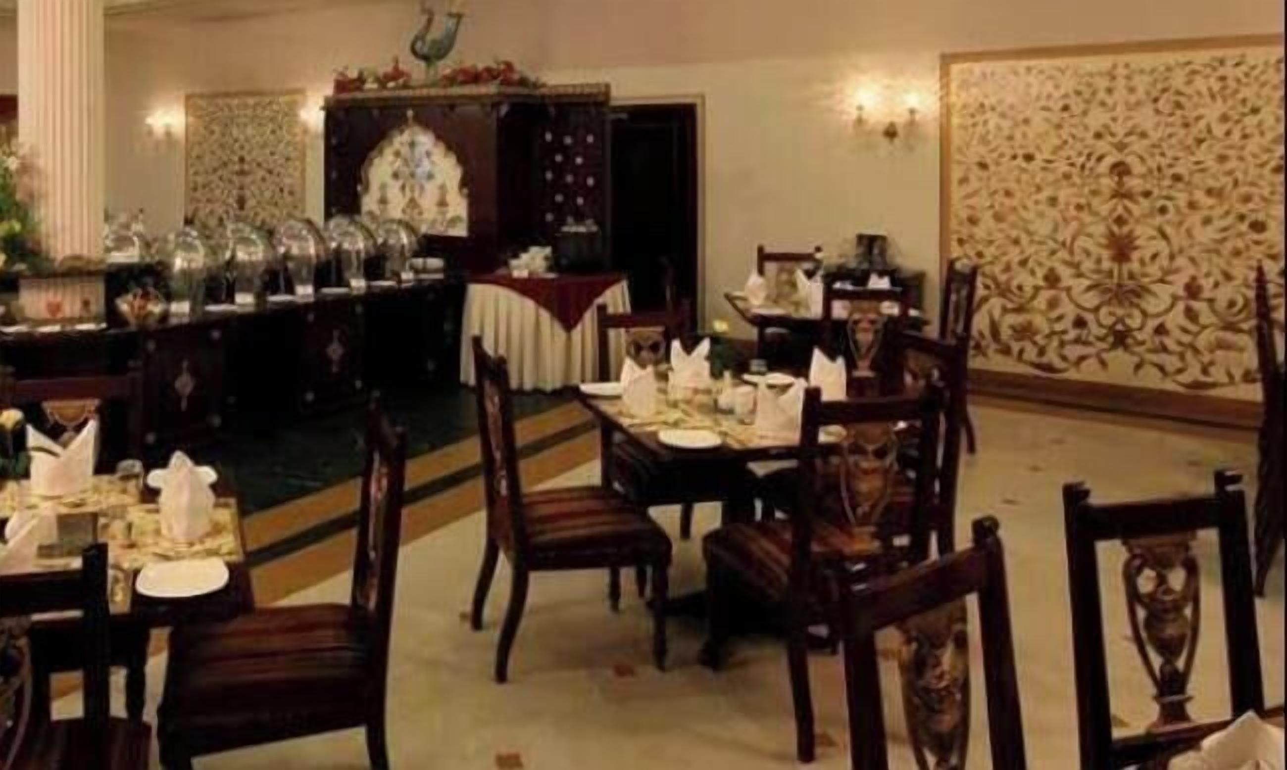 A dining area with tables set for service, a decorative wall, and a patterned backdrop.