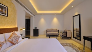Una camera d'albergo moderna con un letto grande, un divano, un tavolino, uno specchio e un tappeto decorato.