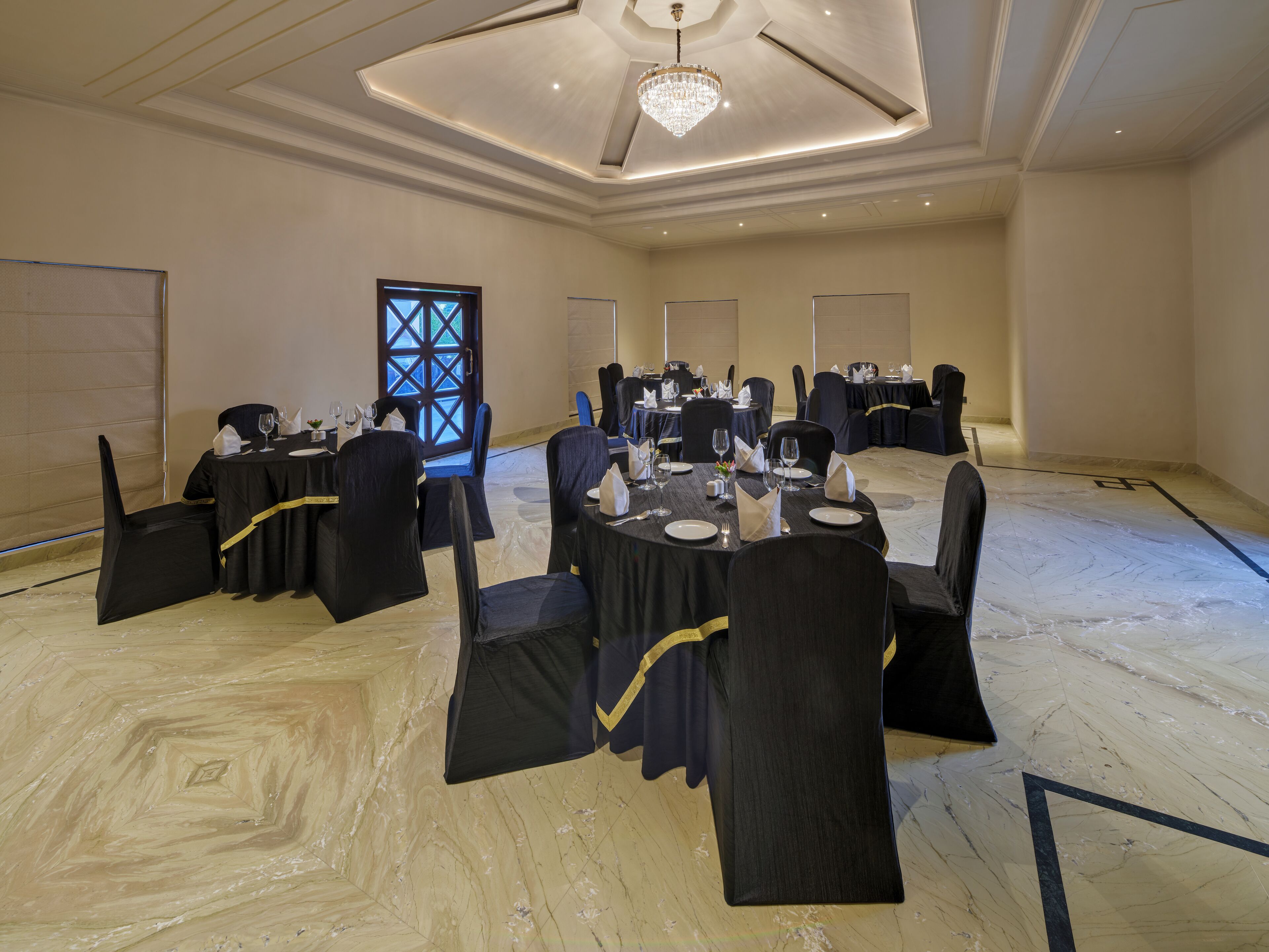 A conference room with round tables, black chairs, and a chandelier.
