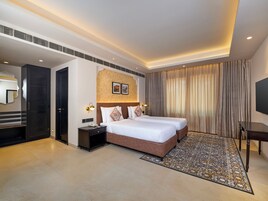 Quarto de hotel moderno com duas camas, um espelho grande, uma TV de tela plana e um tapete estampado.