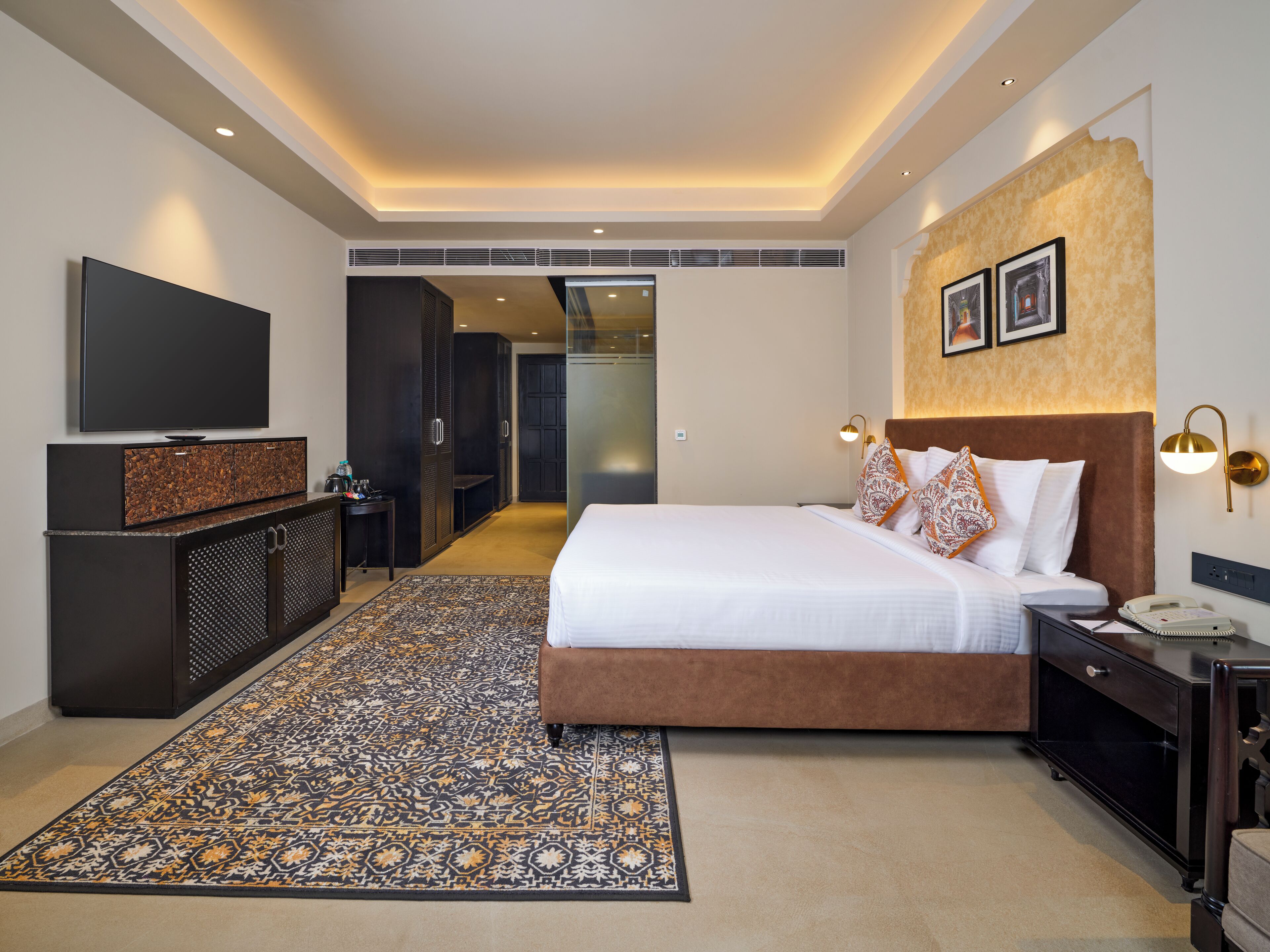 Una habitación de hotel moderna con una cama grande, un televisor, un escritorio y un vestidor.