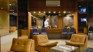 A modern lobby with leather seating, a reception desk, and a television screen. - Hotel Diplomat (Tunis)