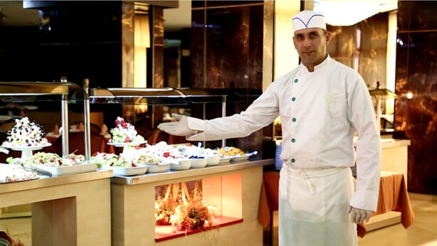 A buffet setup with various dishes and a chef in uniform. - Hotel Diplomat (Tunis)