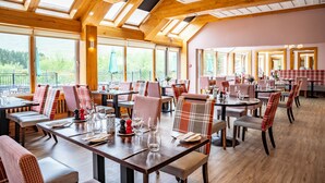 A restaurant with wooden beams, large windows, and tables set for dining. - Delphi Resort (Leenane)