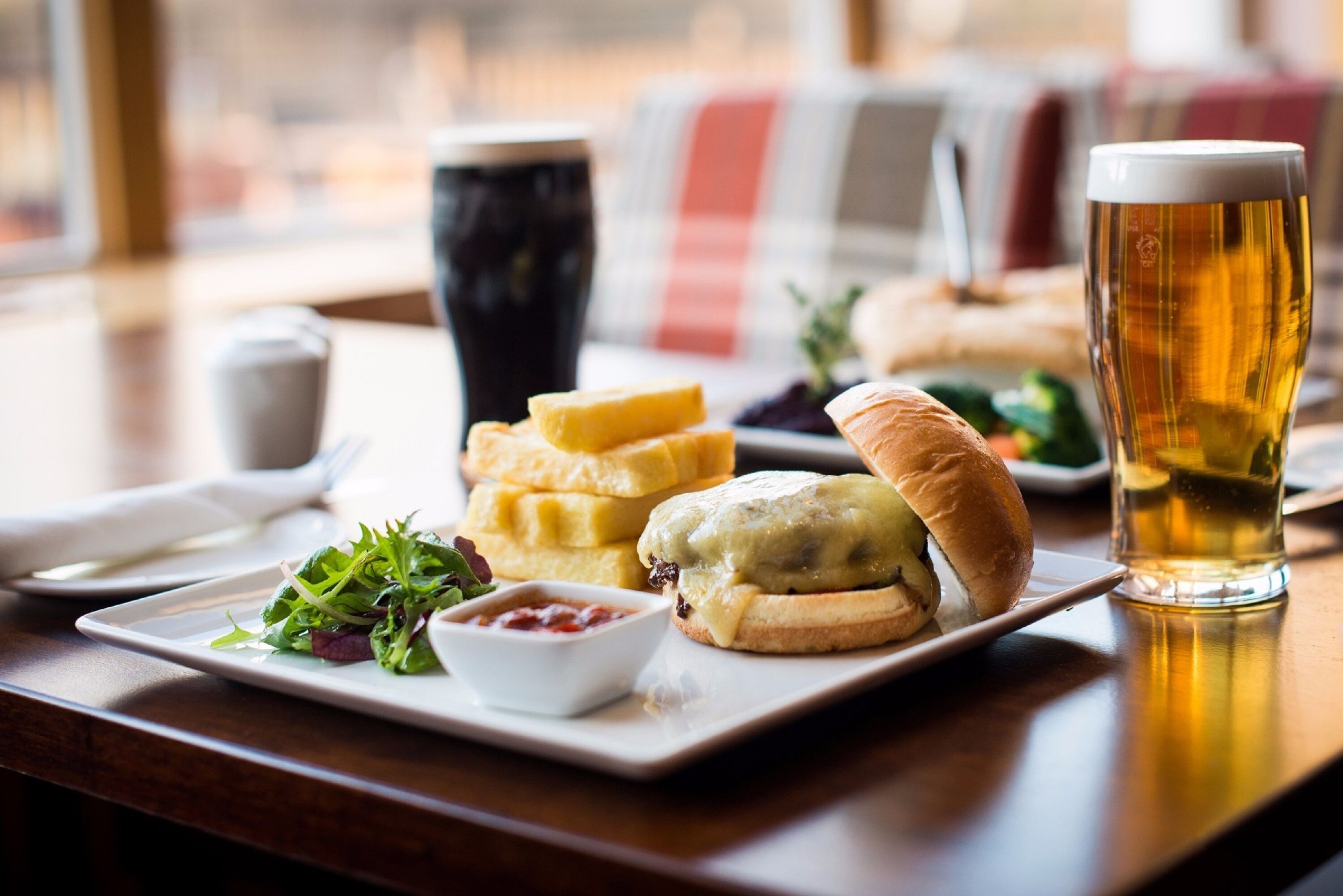 Une table à manger avec une assiette de nourriture, un verre de bière et une tasse de café.