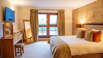 A hotel room with a bed, a desk, a television, a window with curtains, and a view of the outdoors.