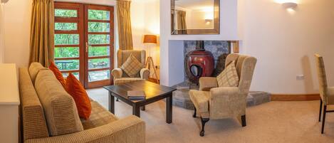 A cozy living room with a sofa, armchairs, a coffee table, and a fireplace.