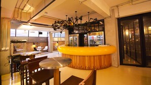 Un bar moderno con una barra amarilla, sillas de madera y un diseño original de ventilador de techo.