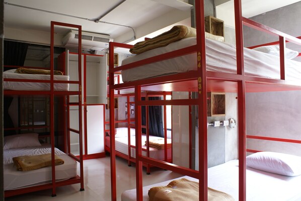 A dormitory-style room with bunk beds, a window with curtains, and an air conditioning unit.