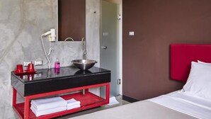 Un baño moderno con un lavamanos negro, tocador rojo y un espejo grande.