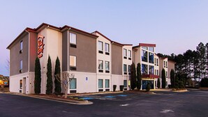 A multi-story hotel with a flat roof, large windows, and a parking lot in front. - Red Roof Inn Locust Grove (Locust Grove)