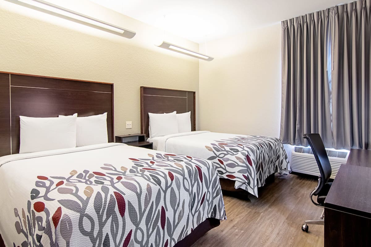 Ein Hotelzimmer mit zwei Betten, einem Schreibtisch und einem Stuhl.