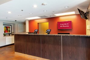 En hotellreception med en skylt som visar att det finns kostnadsfritt Wi-Fi i alla rum, två digitala informationskiosker och en övervakningskamera i taket.