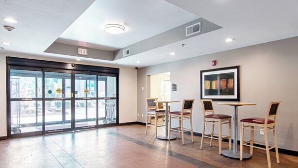 A spacious lobby with a large glass door entrance, multiple seating areas, and a framed artwork on the wall. - Red Roof Inn Locust Grove (Locust Grove)
