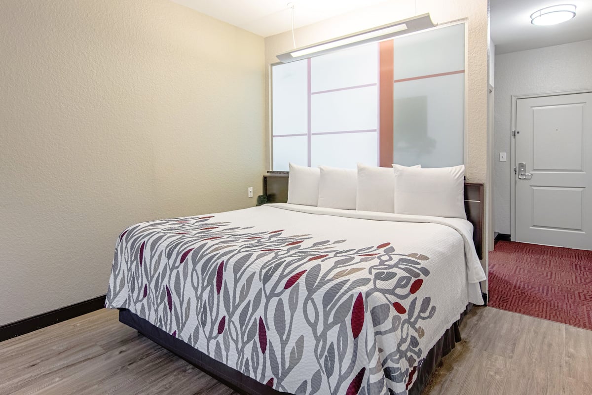 Ein Hotelzimmer mit Bett, Fenster, Tür und einem roten Teppich.