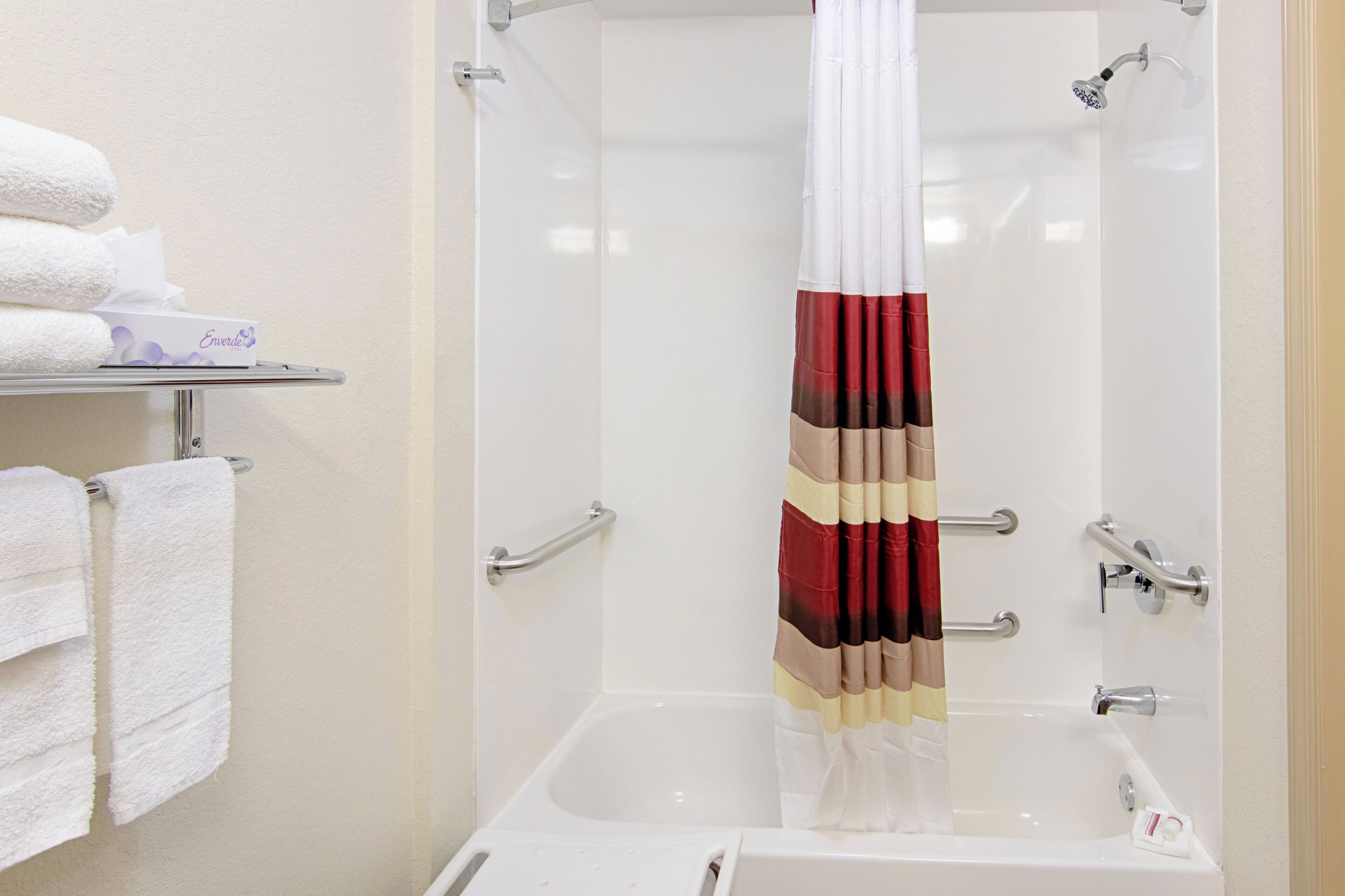 Un baño con bañera, cortina de ducha y un perchero con toallas.
