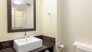 Ein Badezimmer mit einem weißen Waschbecken, einem Spiegel, einem Handtuchhalter und einer Toilette.
