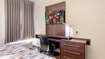 A hotel room with a bed, a desk, a chair, a dresser, and a painting on the wall.