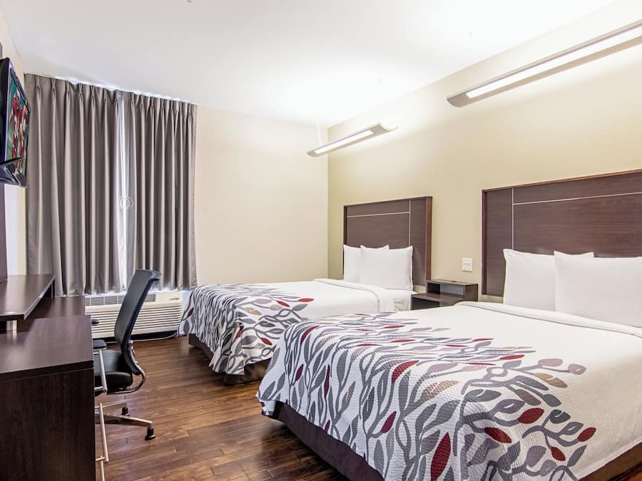 Una habitación de hotel con dos camas, un escritorio, una televisión y una silla.