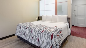 A hotel room with a bed, a window, a door, and a carpeted floor. - Red Roof Inn Locust Grove (Locust Grove)