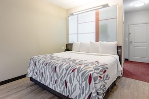 Una habitación de hotel con cama, ventana, puerta y piso alfombrado.