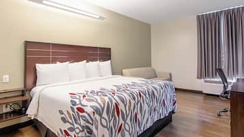 A hotel room with a bed, a desk, and a chair.