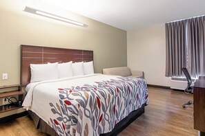 Et hotelværelse med seng, skrivebord og stol.