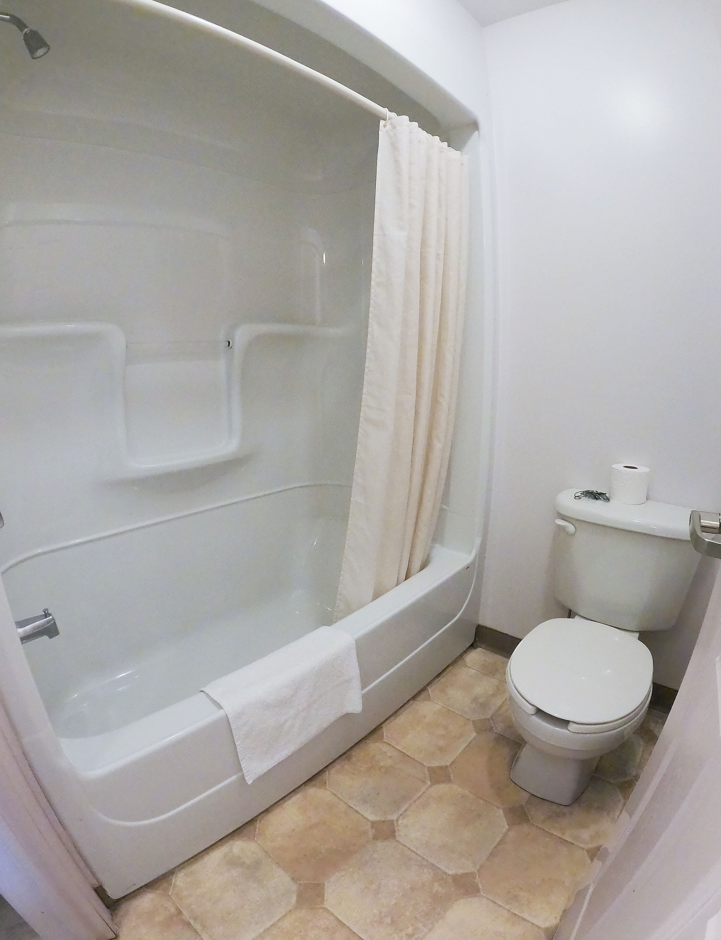 Un baño con bañera, inodoro y cortina de ducha.