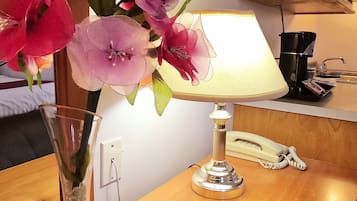 A wooden table with a lamp, a phone, and a vase with flowers.