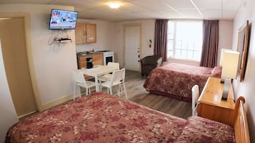 Habitación de hotel con dos camas, un escritorio, una silla, un televisor y una ventana con cortinas.