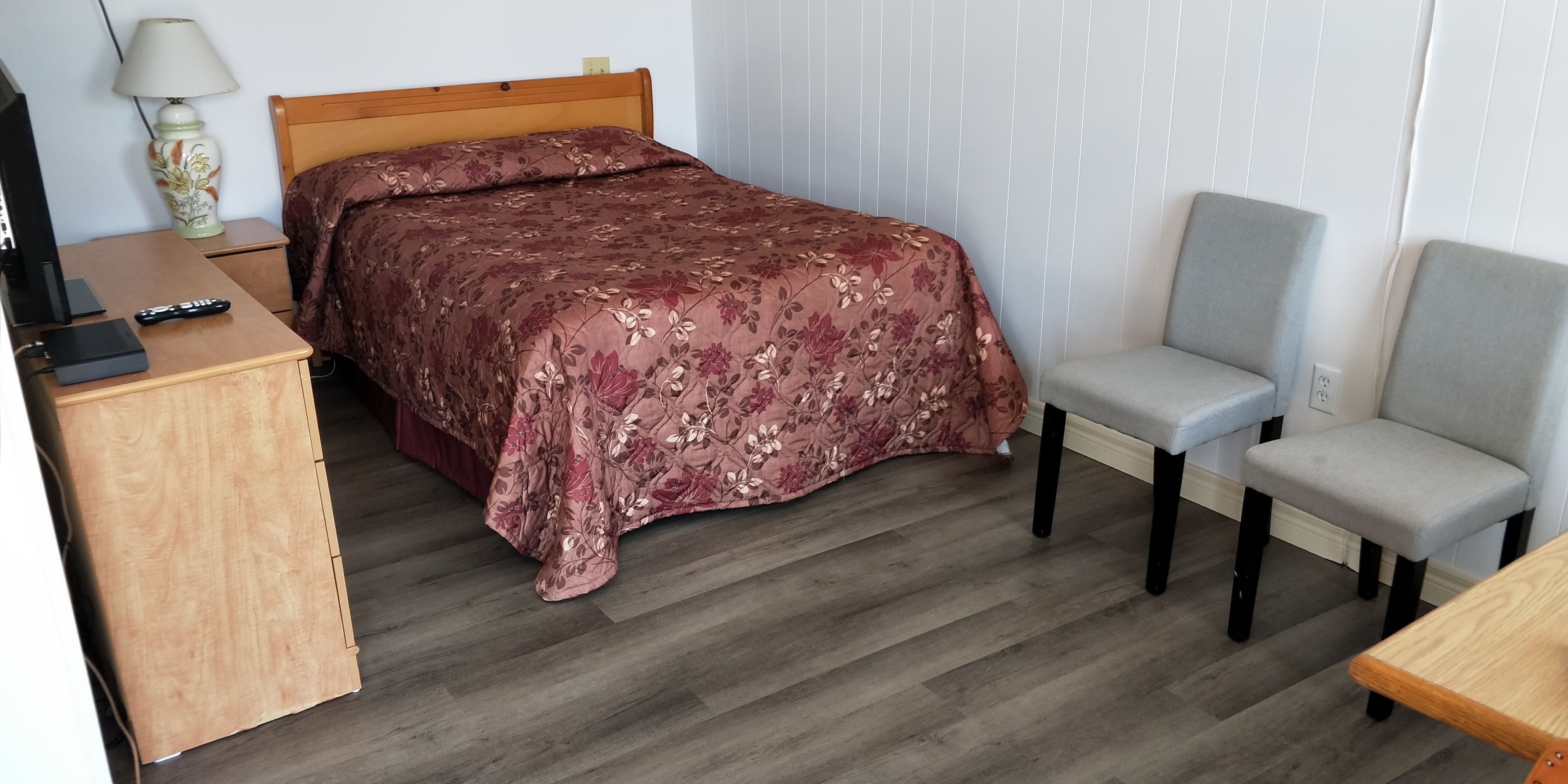A bedroom with a bed, a desk, a chair, and a lamp.