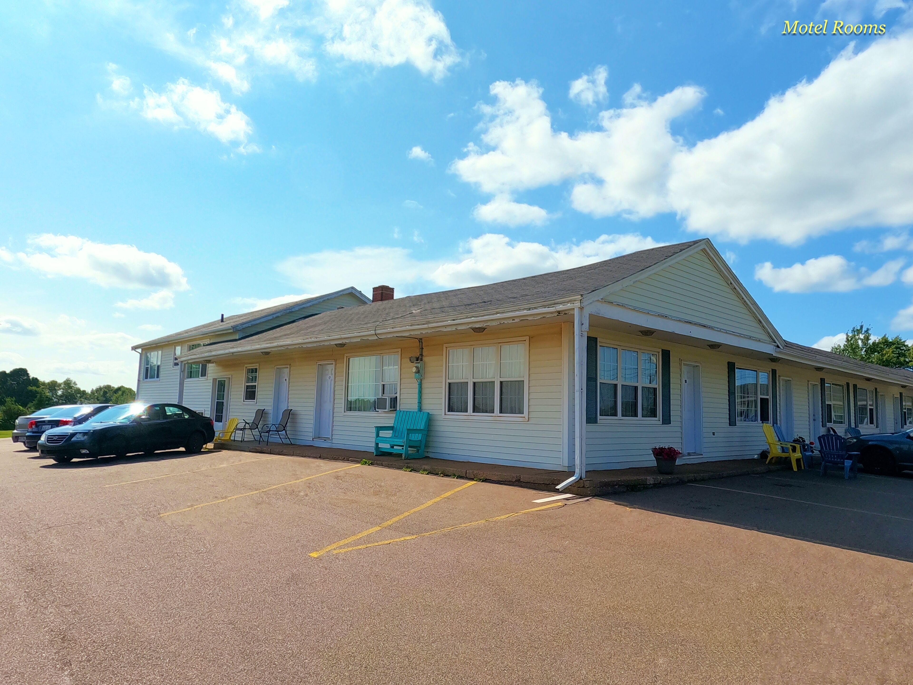 A motel with a single-story structure, a parking lot, and a row of rooms with windows.