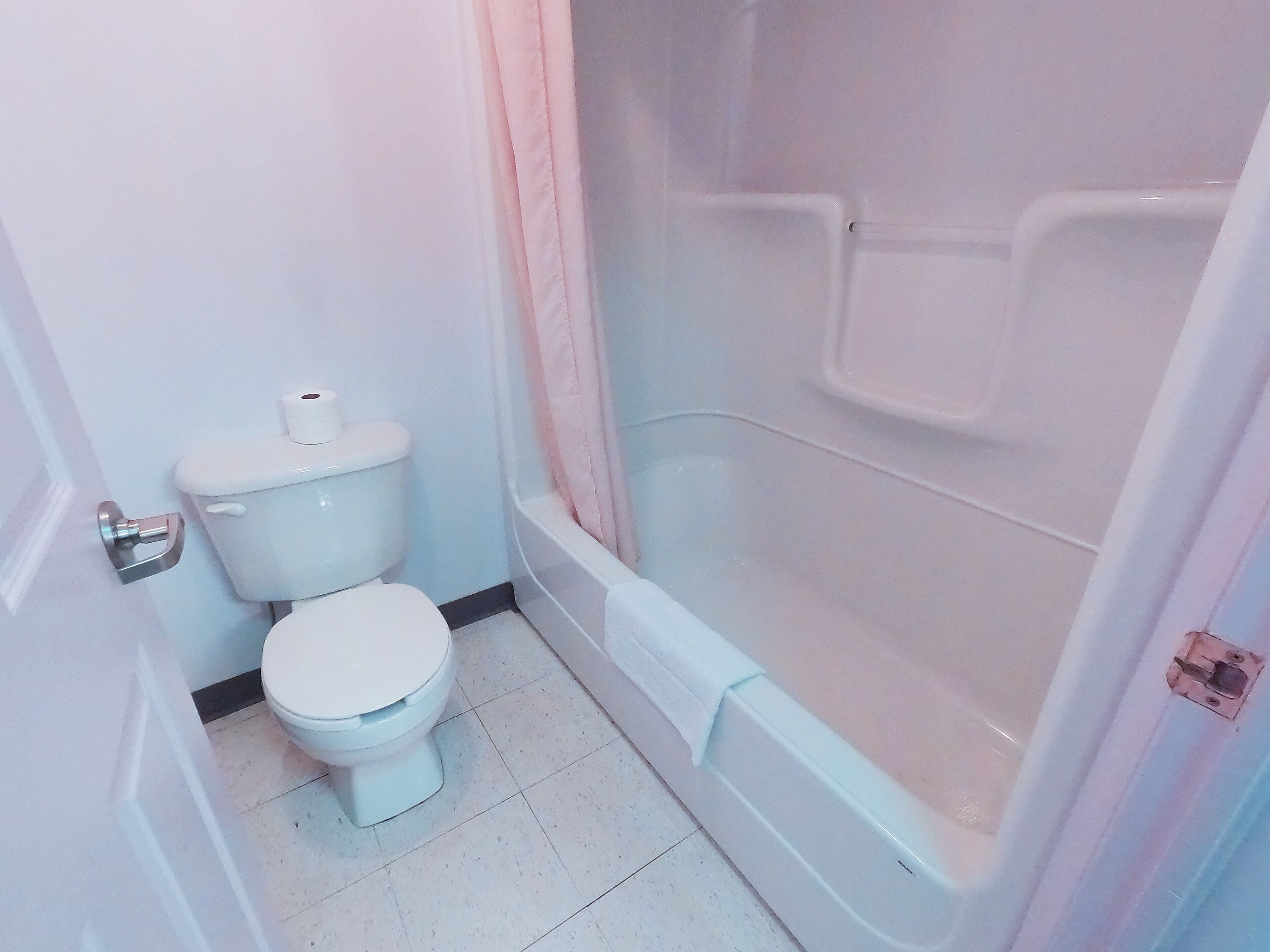 Een badkamer met toilet, bad en douchegordijn.