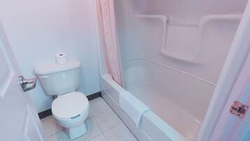 Een badkamer met toilet, bad en douchegordijn.