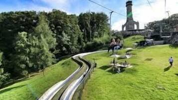 A winding road with a grassy area and a tower-like structure in the background.