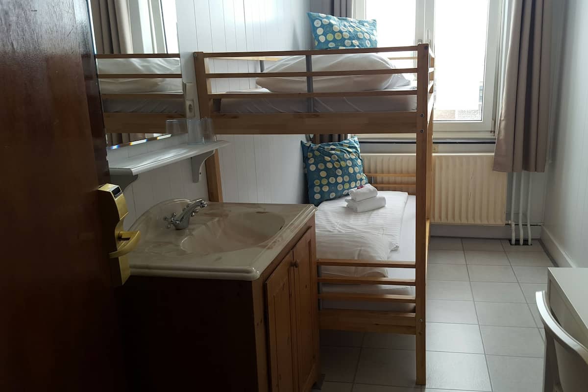 Une chambre avec un lit superposé, un lavabo et une fenêtre.