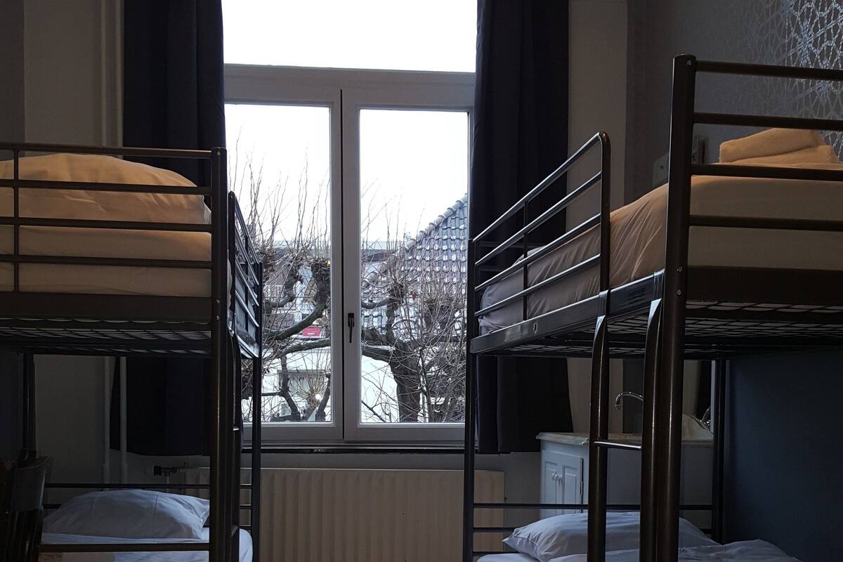 Une chambre avec des lits superposés, une fenêtre donnant sur les arbres et un radiateur.