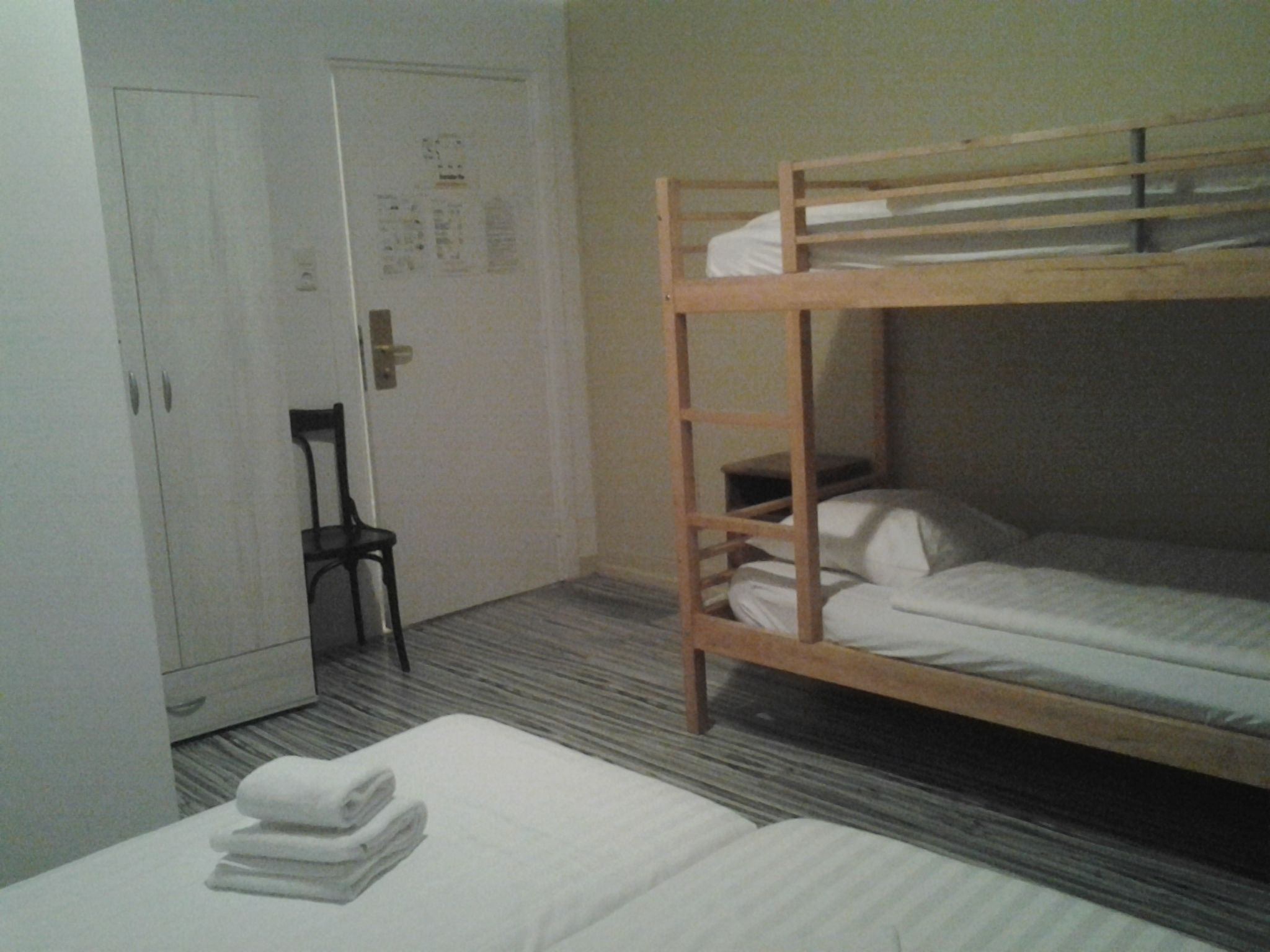 Une chambre avec un lit superposé, une chaise et une armoire.