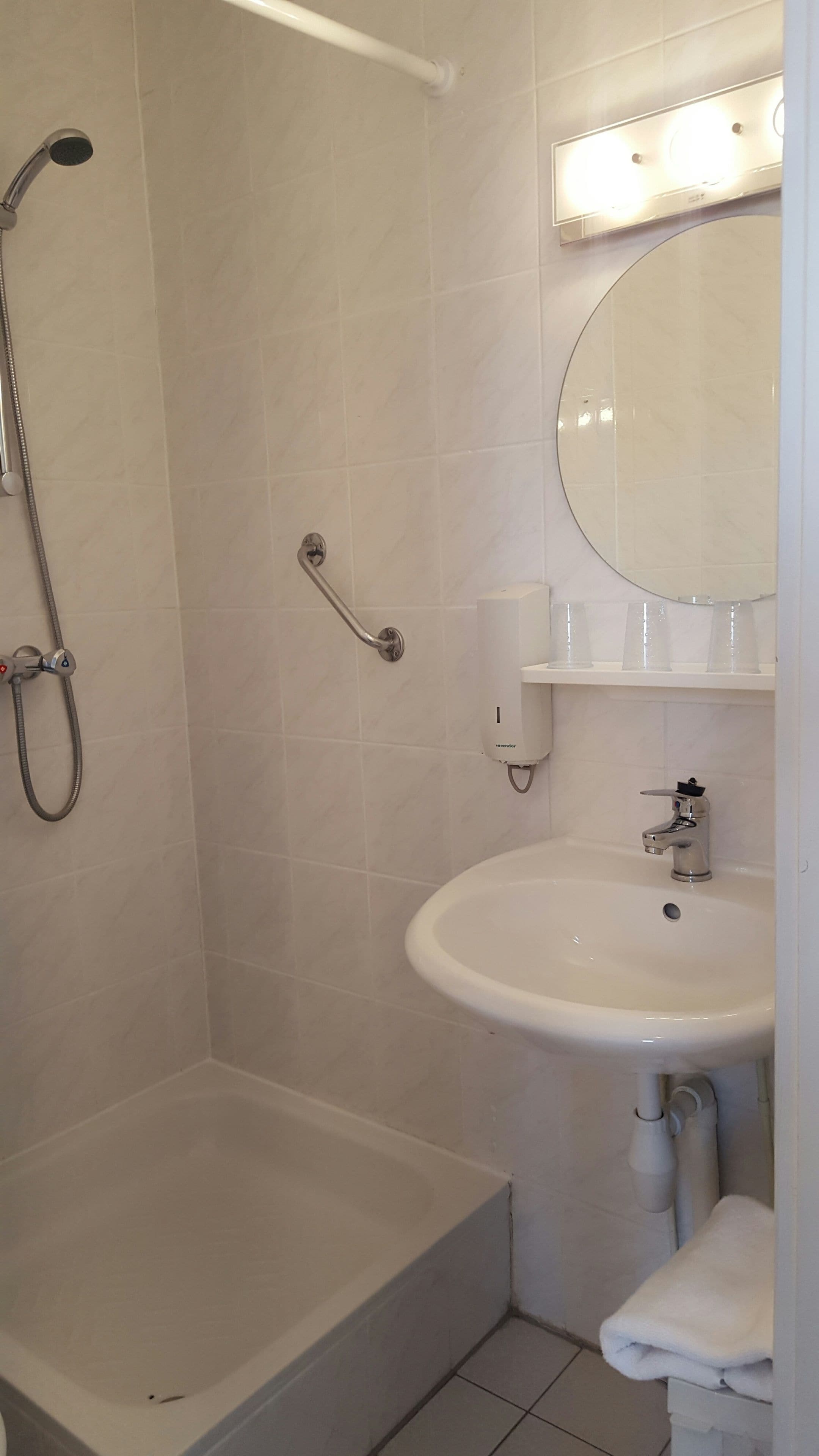 Une salle de bain avec une douche, un lavabo et un miroir.